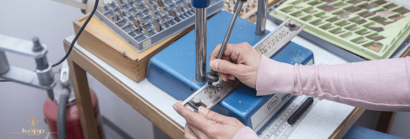 Mitarbeiterin des Juwelier Kopp graviert ein Schmuckstück